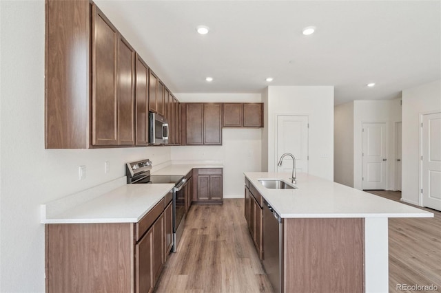 13392 E 110th Way, Commerce City, CO 80022 - kitchen featuring appliances with stainless steel finishes, a sink, light wood-type flooring, a kitchen island with sink, and recessed lighting