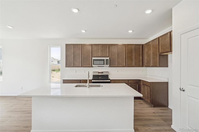 13392 E 110th Way, Commerce City, CO 80022 - kitchen featuring stainless steel appliances, a sink, light wood-style floors, light countertops, and an island with sink