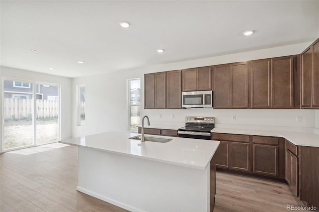13392 E 110th Way, Commerce City, CO 80022 - kitchen with appliances with stainless steel finishes, a sink, light wood-type flooring, light countertops, and a center island with sink