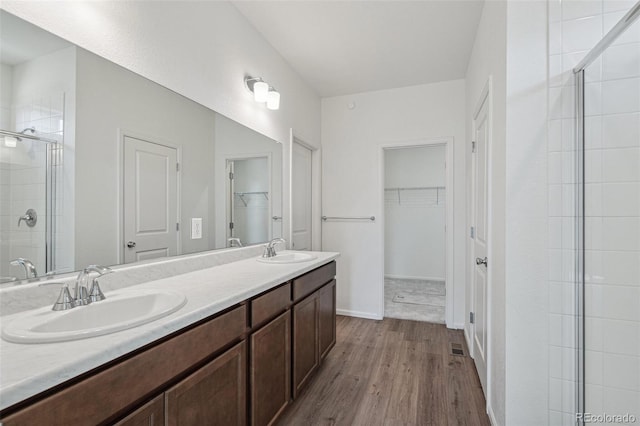 13392 E 110th Way, Commerce City, CO 80022 - bathroom with wood finished floors, a stall shower, a spacious closet, double vanity, and baseboards