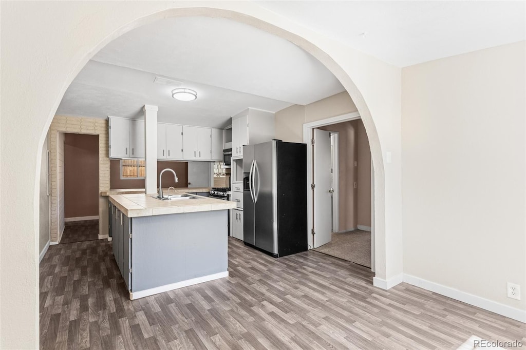 kitchen with white cabinetry, dark hardwood / wood-style floors, sink, and stainless steel fridge with ice dispenser