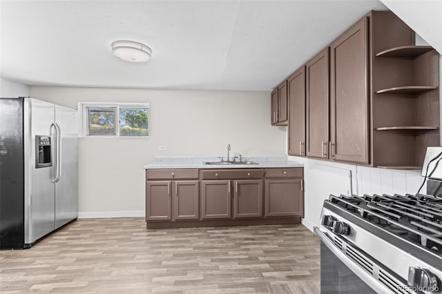 kitchen featuring sink, appliances with stainless steel finishes, dark brown cabinets, and light wood-type flooring