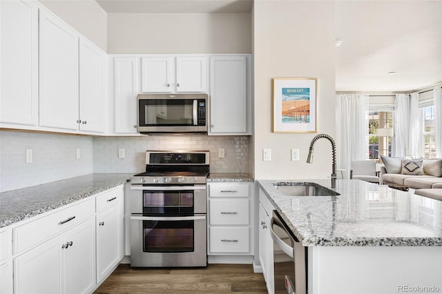 14833 E Crestridge Dr, Centennial, CO 80015 - kitchen with stainless steel appliances, a sink, dark wood-style flooring, light stone countertops, and white cabinetry