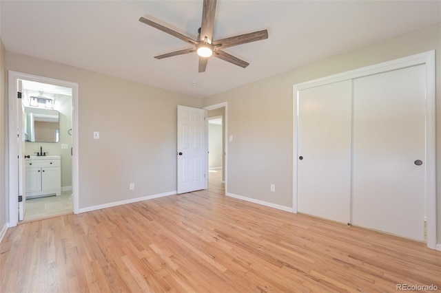 unfurnished bedroom featuring ceiling fan, sink, a closet, ensuite bath, and light hardwood / wood-style floors