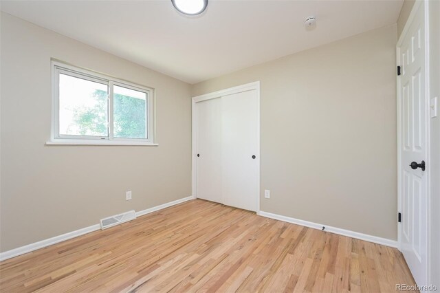 unfurnished bedroom with light wood-type flooring and a closet