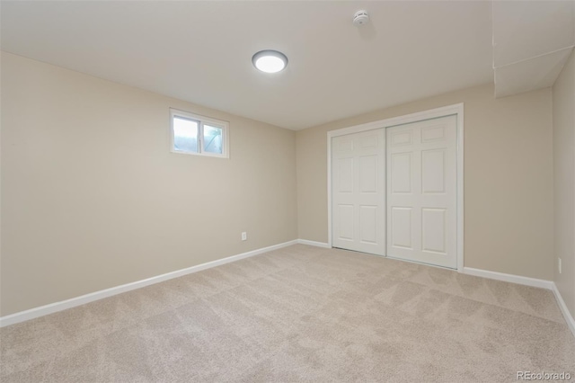 unfurnished bedroom featuring light carpet, baseboards, and a closet