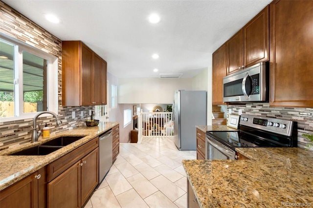 9325 Meade St, Westminster, CO 80031 - kitchen with stainless steel appliances, backsplash, light stone countertops, light tile patterned floors, and recessed lighting