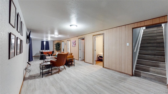 dining space featuring light hardwood / wood-style flooring, wooden walls, and a textured ceiling