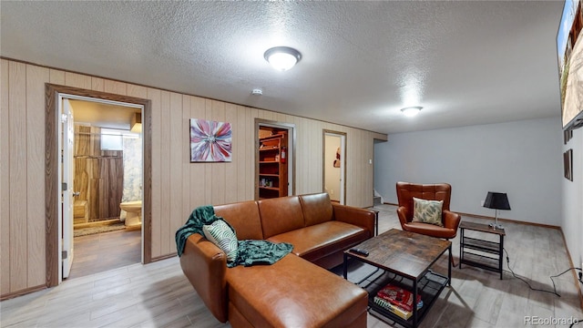 living room with light hardwood / wood-style floors, a textured ceiling, and wood walls