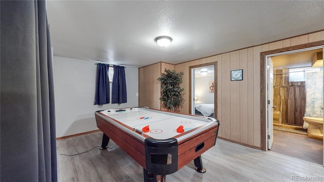 rec room with wood-type flooring, a textured ceiling, and wood walls