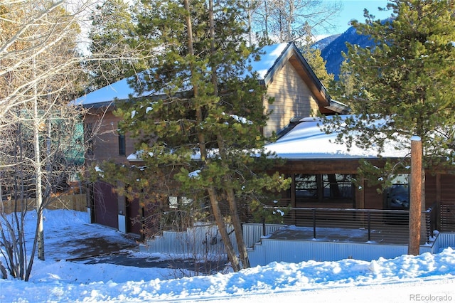 view of snow covered exterior featuring a mountain view, a porch, and a garage