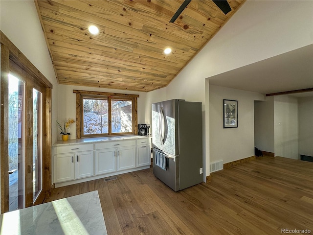 kitchen with wooden ceiling, white cabinets, vaulted ceiling, stainless steel fridge, and light hardwood / wood-style floors