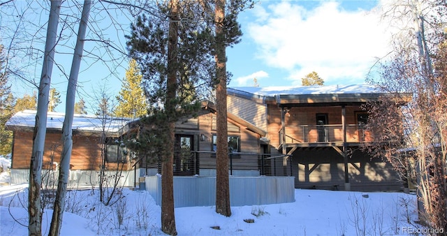 snow covered back of property with a balcony