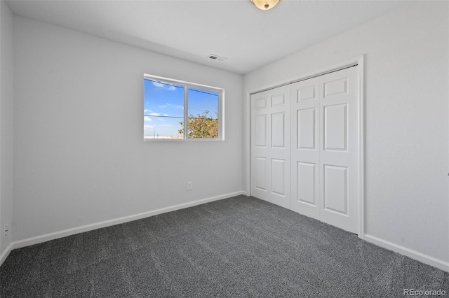 unfurnished bedroom with dark colored carpet and a closet