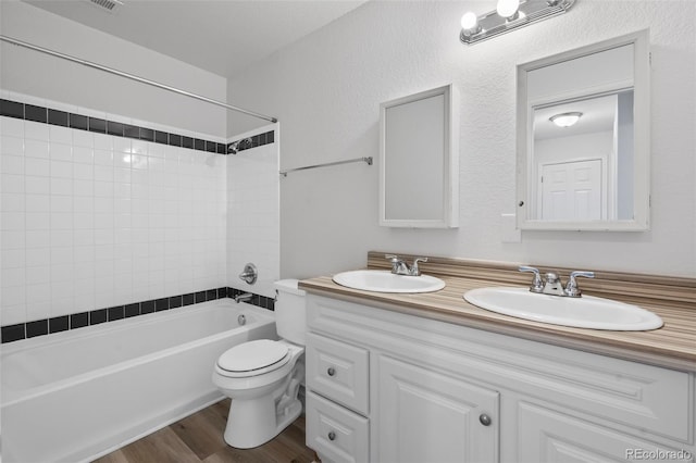 full bathroom with vanity, wood-type flooring, tiled shower / bath combo, and toilet