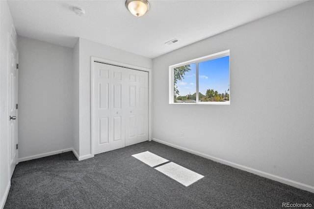 unfurnished bedroom featuring a closet and dark carpet