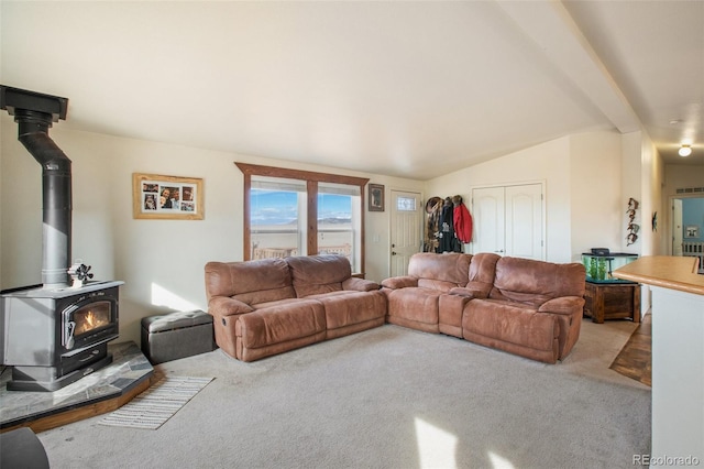 living room with light carpet, lofted ceiling with beams, and a wood stove