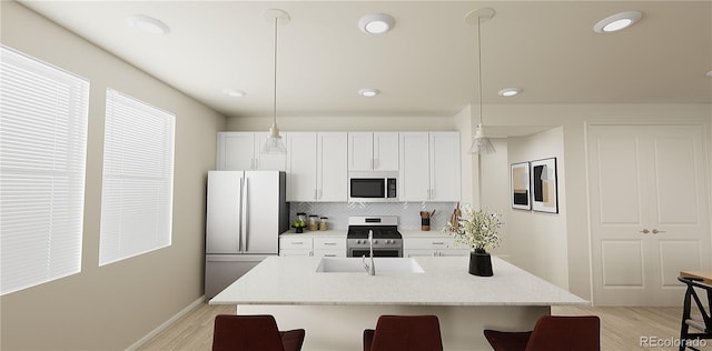 kitchen featuring tasteful backsplash, stainless steel appliances, white cabinetry, pendant lighting, and light hardwood / wood-style flooring