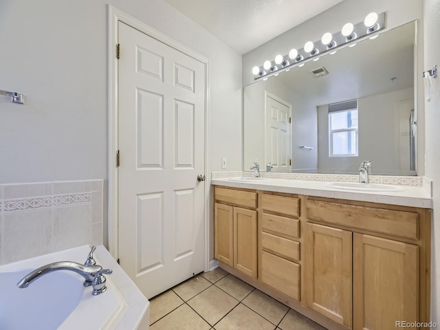 bathroom with tile patterned flooring, a bath, and vanity