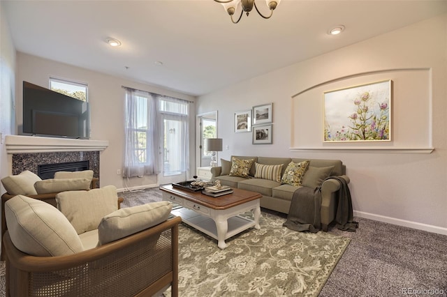 living room with a high end fireplace, carpet flooring, an inviting chandelier, and plenty of natural light