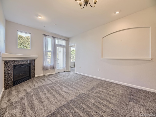 unfurnished living room featuring carpet flooring, plenty of natural light, and a high end fireplace