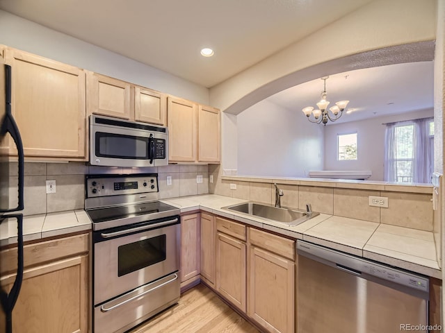 kitchen featuring appliances with stainless steel finishes, tile countertops, tasteful backsplash, and sink