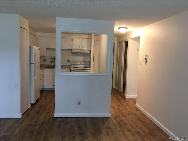 kitchen featuring white appliances, dark wood finished floors, a sink, under cabinet range hood, and white cabinetry