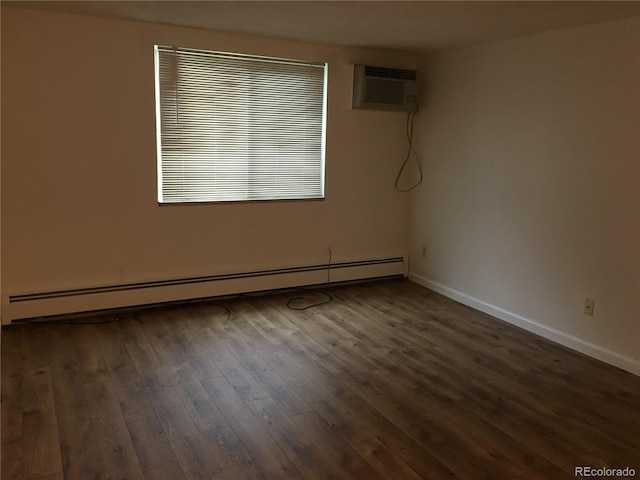 spare room with baseboard heating, a wall mounted air conditioner, baseboards, and wood finished floors