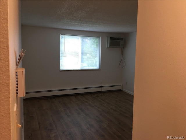 empty room with a baseboard heating unit, wood finished floors, a wall mounted air conditioner, and a textured ceiling