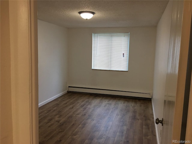 spare room featuring a baseboard heating unit, wood finished floors, baseboards, and a textured ceiling