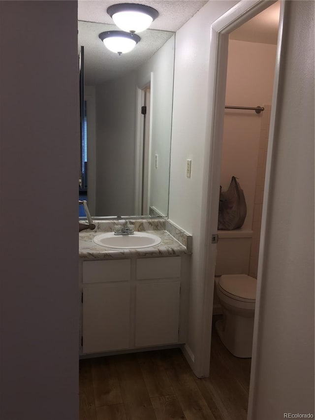 half bathroom featuring vanity, toilet, and wood finished floors