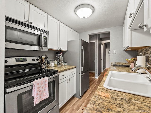 100 S Clarkson St Unit 202, Denver, CO 80209 - kitchen with appliances with stainless steel finishes, light countertops, white cabinets, light wood finished floors, and a textured ceiling