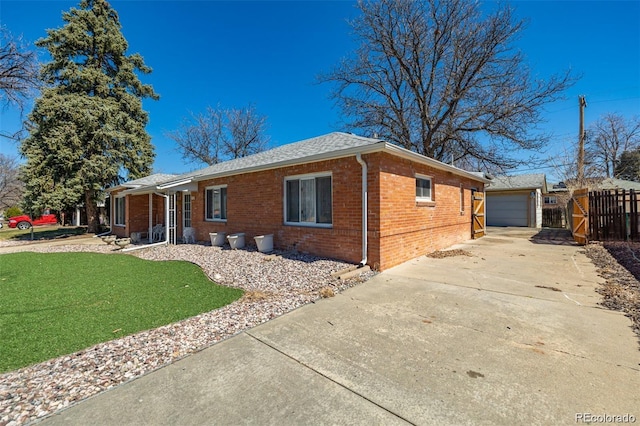 938 Racine St, Aurora, CO 80011 - view of front facade featuring brick siding, a detached garage, roof with shingles, and concrete driveway