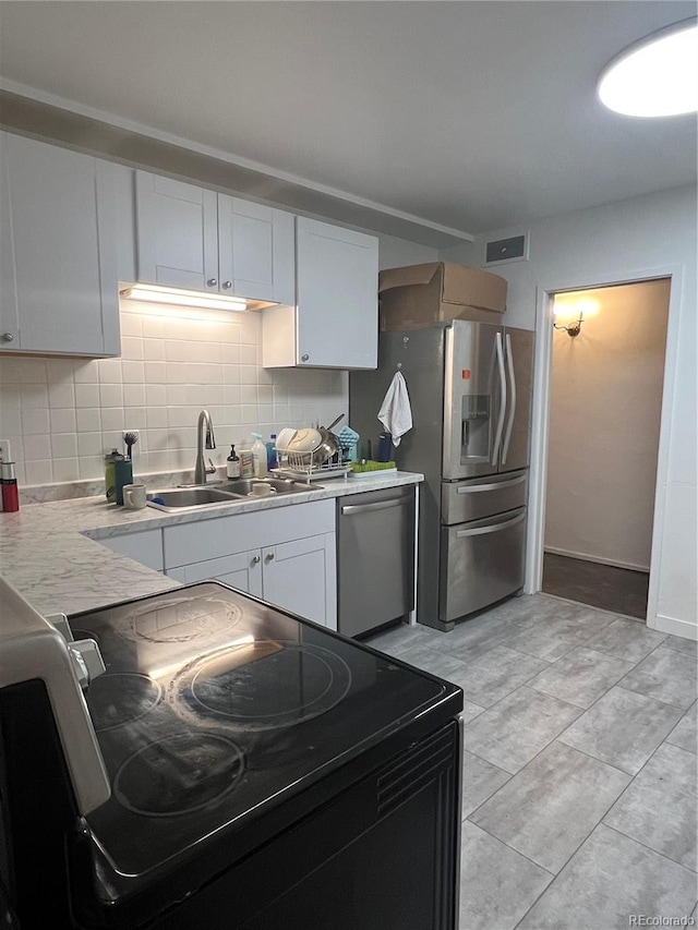938 Racine St, Aurora, CO 80011 - kitchen with appliances with stainless steel finishes, decorative backsplash, light countertops, and white cabinetry