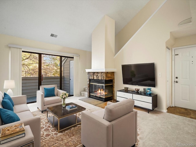 living room with a stone fireplace, vaulted ceiling, and carpet