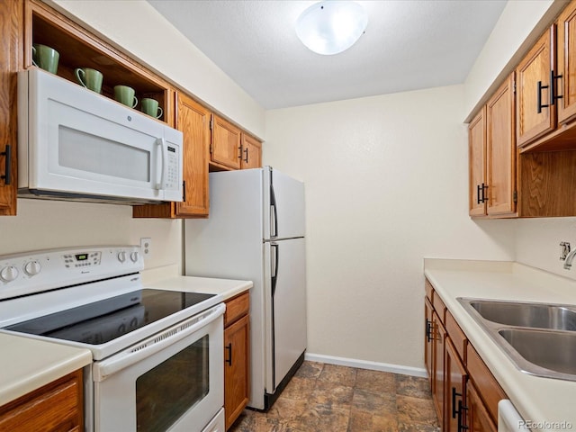 kitchen featuring light countertops, white appliances, brown cabinetry, and a sink