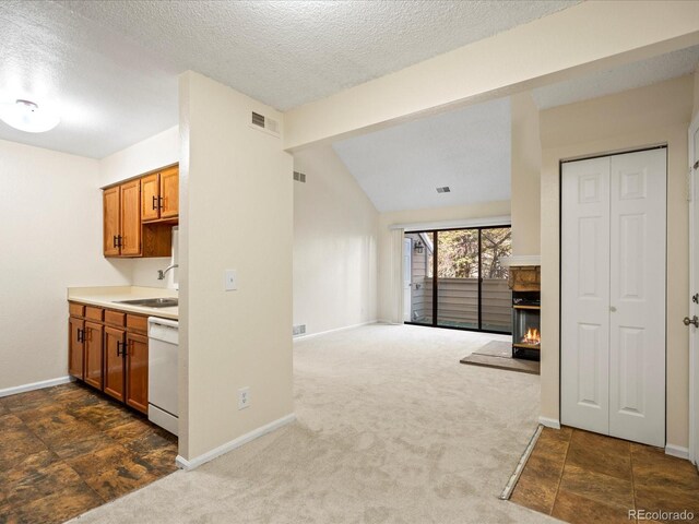 kitchen with a sink, visible vents, dishwasher, brown cabinetry, and dark carpet