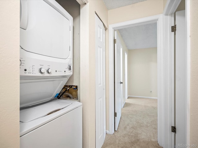 laundry room with a textured ceiling, light carpet, laundry area, stacked washer / dryer, and baseboards