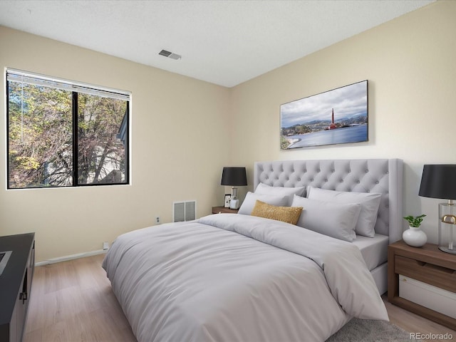 bedroom featuring light wood-type flooring, baseboards, and visible vents