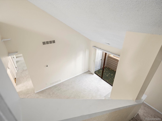 interior space featuring a textured ceiling, carpet, visible vents, and baseboards