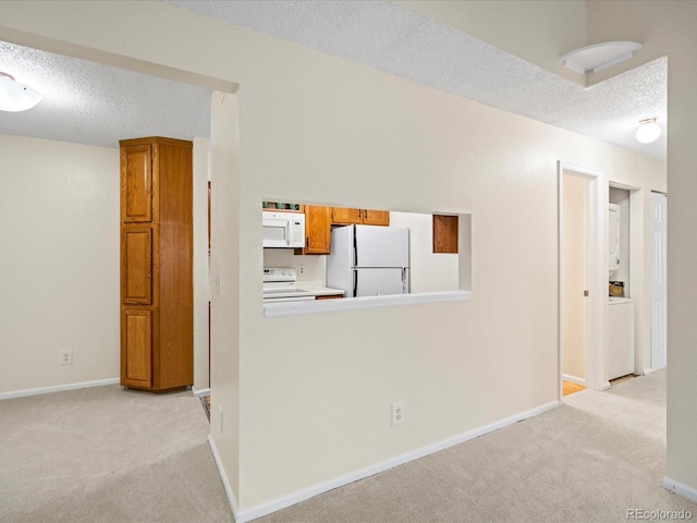 hallway with light carpet, baseboards, and a textured ceiling