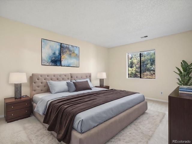 bedroom featuring light colored carpet, visible vents, a textured ceiling, and baseboards