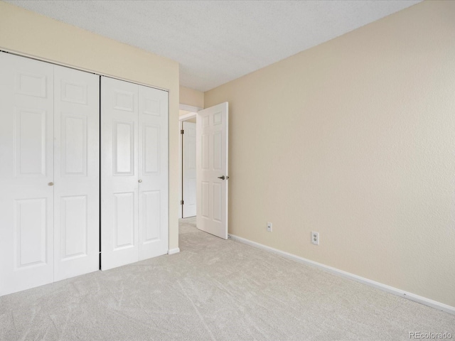 unfurnished bedroom with carpet, a closet, and baseboards