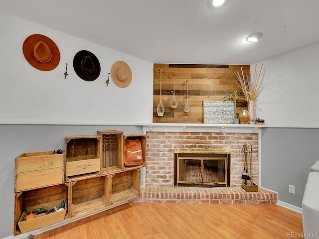 living room with a fireplace, wood-type flooring, and wood walls