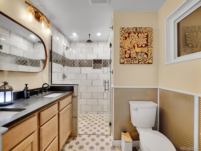 bathroom with vanity, toilet, walk in shower, and tile walls