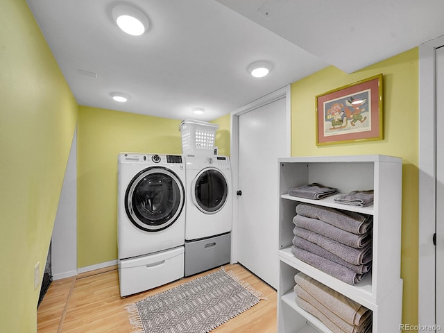 clothes washing area featuring washer and clothes dryer and wood-type flooring