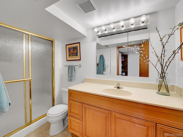 bathroom with tile patterned floors, vanity, toilet, and a shower with shower door