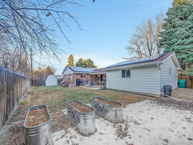 back of property with a lawn, solar panels, a patio area, and a shed