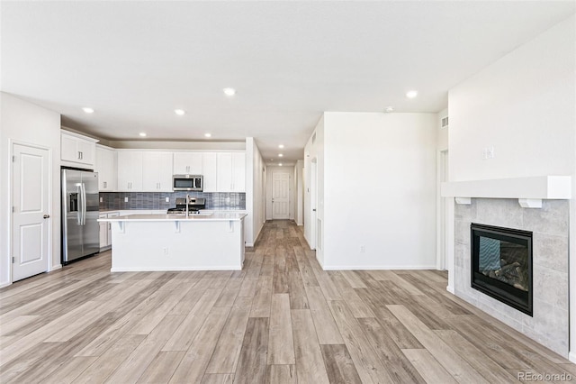 kitchen featuring open floor plan, light countertops, decorative backsplash, stainless steel appliances, and a sink