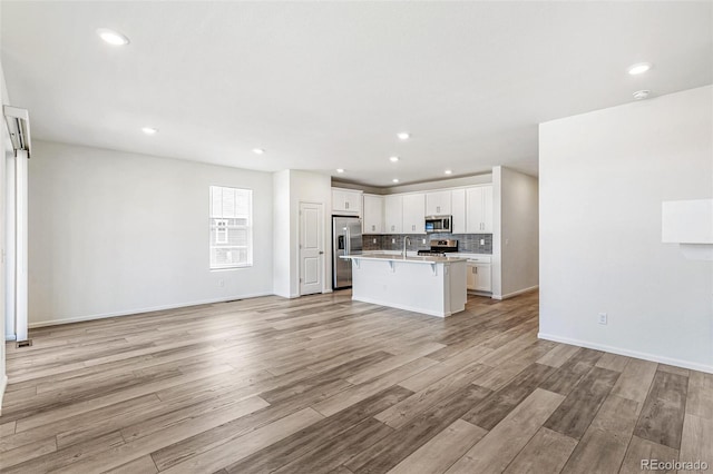 kitchen featuring tasteful backsplash, open floor plan, appliances with stainless steel finishes, and a kitchen breakfast bar